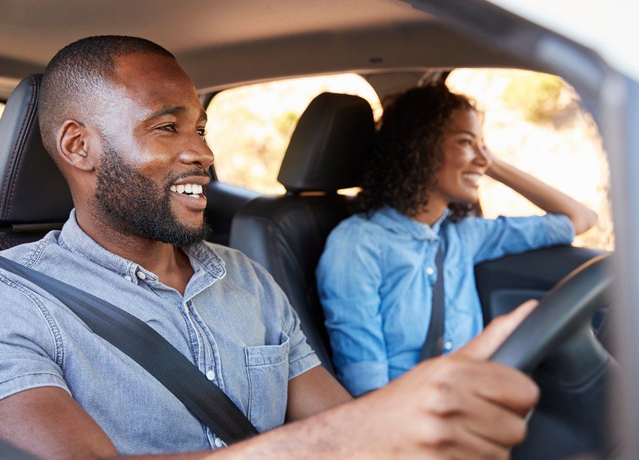 A smiling couple driving in their vehicle