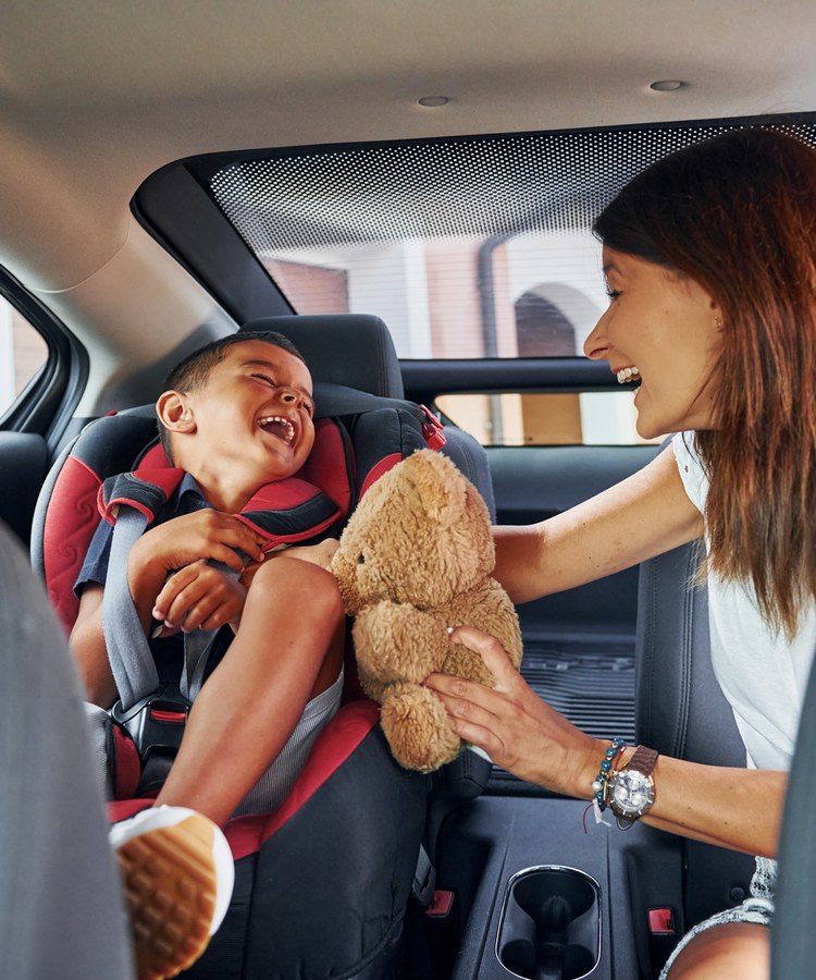 A smiling mother and son in the backseat of a car